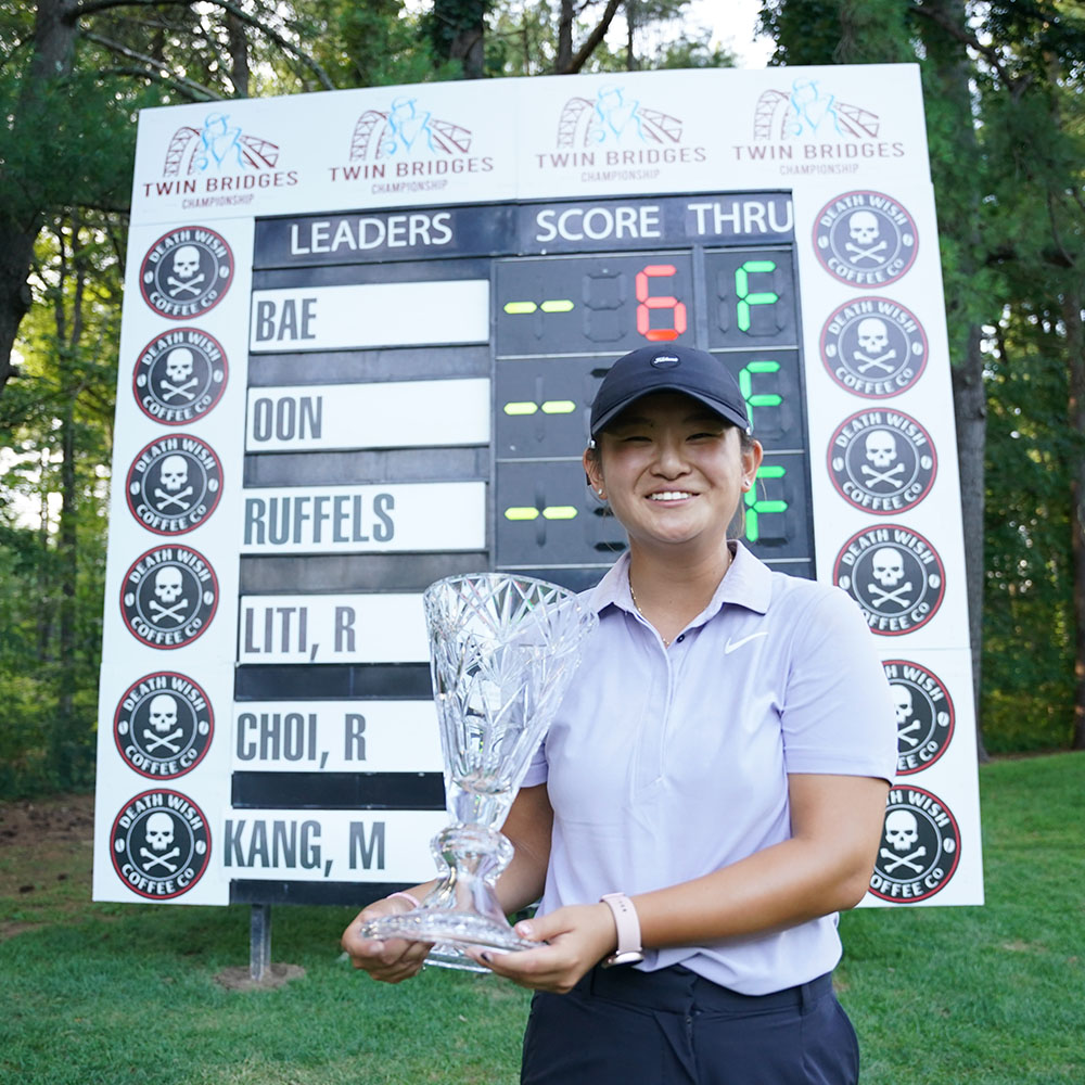 Jenny Bae holding trophy in front of scoreboard